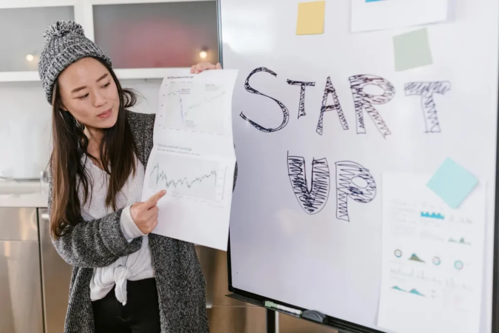 Seorang perempuan mempresentasikan grafik pertumbuhan bisnis dalam sesi pitching startup