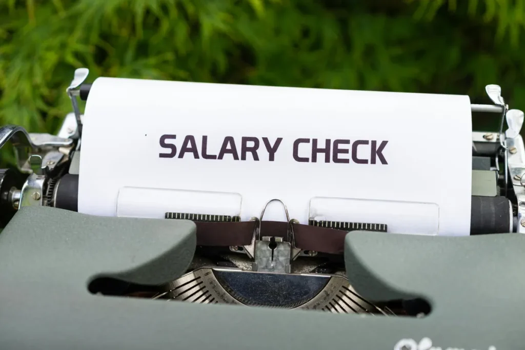 Mesin tik vintage mengetik tulisan Salary Check di atas kertas, melambangkan slip gaji dan penggajian